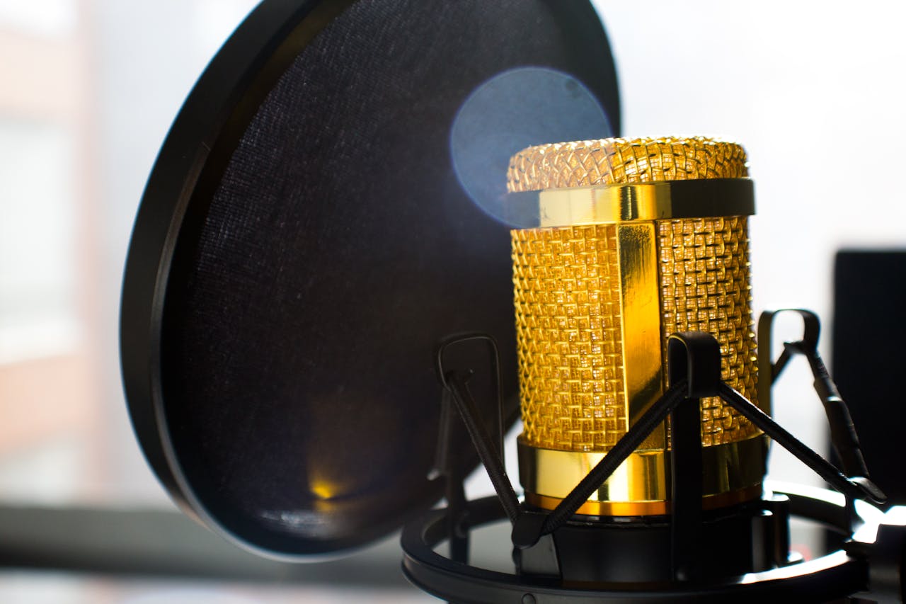 Close-up of a gold studio microphone with pop filter, ideal for recording and broadcasting.